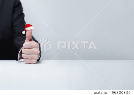 Hand is showing thumb up, finger in Christmas hat, holiday, New Year bonus concept 96300336