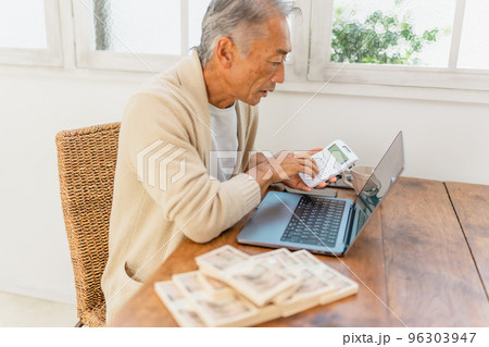 リビングでお金の計算をする男性 リビングでお金の計算をする男性 96303947