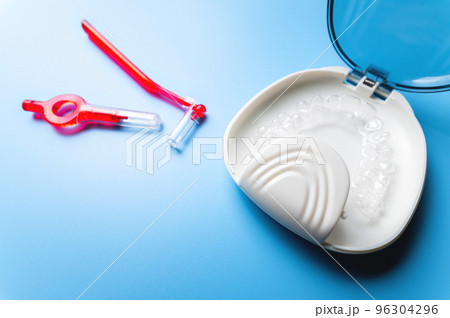 close-up, white box with plastic braces inside and red interdental brush. orthodontic care and cosmetology 96304296