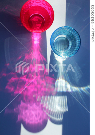 Glittering colored glasses of water on blue background in sunlight. Sunlight through glass of water.  96305055