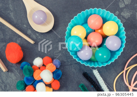 Colorful pompoms, balls and rubber erasers using for playing and development of kids motor skills 96305445