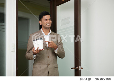 Smiling businessman bringing take-out coffee for himself and colleague in the morning Smiling businessman bringing take-out coffee for himself and colleague in the morning 96305466