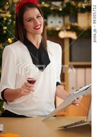 Portrait of smiling female entrepreneur with clipboard rising wine glass at Christmas celebration 96305752