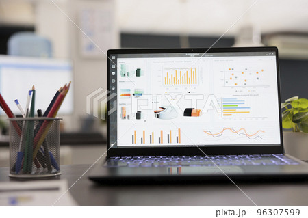 Portable computer with statistical infographics on a desk in an empty modern office. Project stats financial data sales charts on laptop in inside workspace, strategy analysis accounting concept. Portable computer with statistical infographics on a desk in an empty modern office. Project stats financial data sales charts on laptop in inside workspace, strategy analysis accounting concept. 96307599