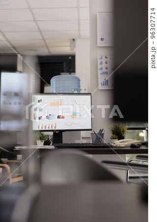 Marketing department of a company with market growth graphics and sales analysis on a desktop computer monitor. Empty office with no staff working during break time. 96307714