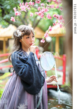Beautiful young woman with dark blue Chinese lolita dress with Chinese garden Beautiful young woman with dark blue Chinese lolita dress with Chinese garden 96307931