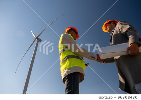 Senior engineer meets technician under operating windmill Senior engineer meets technician under operating windmill 96308430