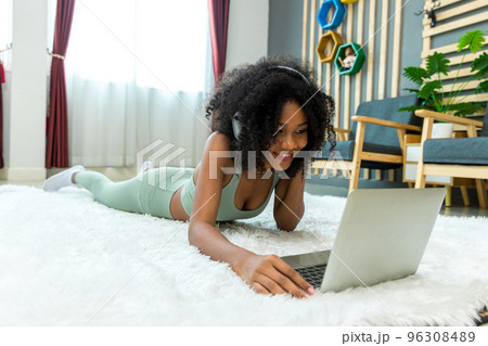 Woman lying on floor and using laptop at home in living room Woman lying on floor and using laptop at home in living room 96308489