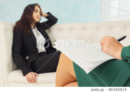 woman sitting on sofa talking to his therapist at therapy session woman sitting on sofa talking to his therapist at therapy session 96308824