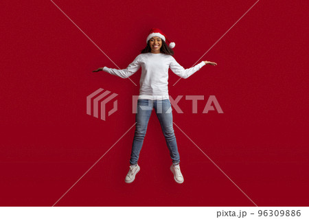 Beautiful african american female model wear santa hat jumping up Beautiful african american female model wear santa hat jumping up 96309886