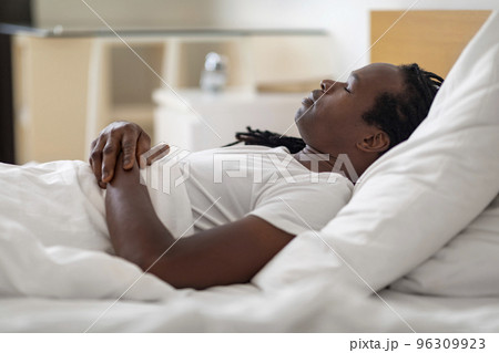 Side View Of Young Black Male Sleeping In Bed At Home 96309923