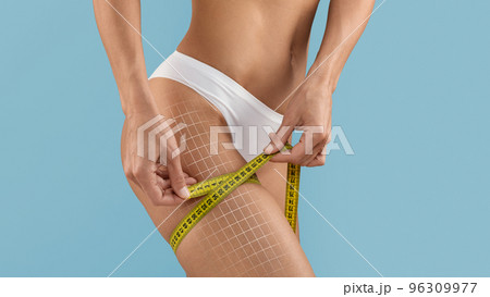 Lipolysis Concept. Slim Female In Underwear Measuring Thigh Size With Tape 96309977