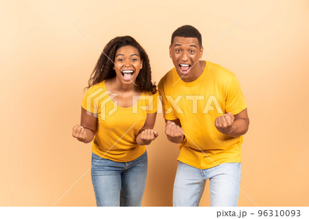 Hooray. Euphoric black spouses shaking clenched fists and exclaiming with excitement, celebrating success 96310093