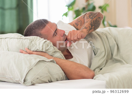 Peaceful man sleeping on his side in morning and yawning Peaceful man sleeping on his side in morning and yawning 96312699