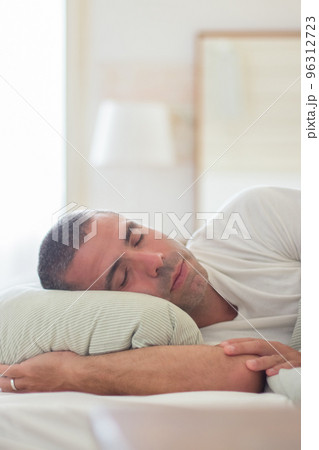 Carefree Caucasian man lying on pillow in bed and sleeping Carefree Caucasian man lying on pillow in bed and sleeping 96312723