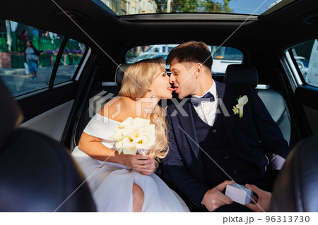 the bride and groom kiss in the back seat of the car. happy newlyweds. the bride and groom kiss in the back seat of the car. happy newlyweds. 96313730
