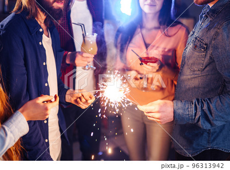Group of happy people holding sparklers at party. Young people celebrating New Year together. Group of happy people holding sparklers at party. Young people celebrating New Year together. 96313942