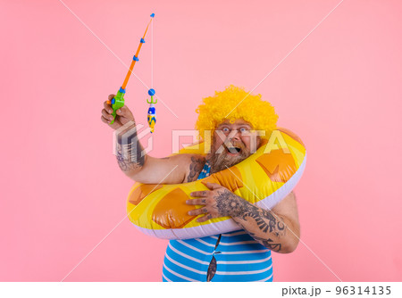 Fat happy man with wig in head plays with the fishing rod Fat happy man with wig in head plays with the fishing rod 96314135