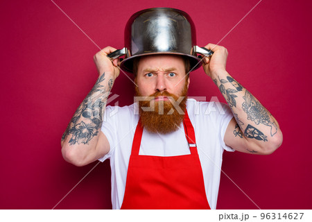 worried chef with beard and red apron plays with pot 96314627