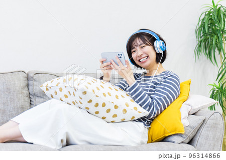 ソファに座ってヘッドフォンで音楽を聴く女性 ソファに座ってヘッドフォンで音楽を聴く女性 96314866