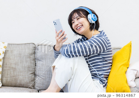 ソファに座ってヘッドフォンで音楽を聴く女性 ソファに座ってヘッドフォンで音楽を聴く女性 96314867