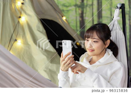 お家時間　ハンモックでくつろぎながらスマートフォンを使う女性 96315836