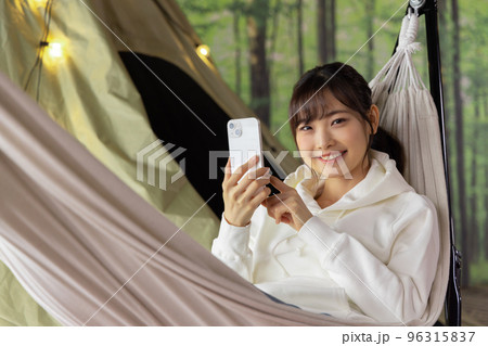 お家時間　ハンモックでくつろぎながらスマートフォンを使う女性 96315837