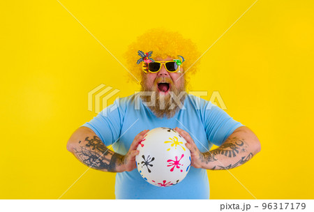 Fat man with wig in head and sunglasses have fun with a ball 96317179