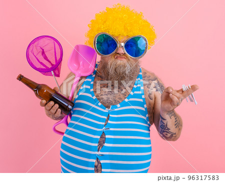 Fat man with beard and wig smokes cigarettes and drinks beer 96317583