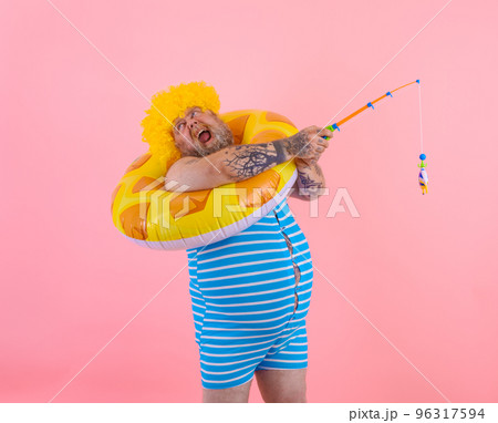 Fat stressed man with wig in head plays with the fishing rod Fat stressed man with wig in head plays with the fishing rod 96317594