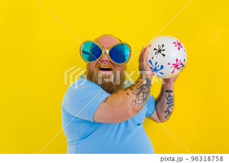 Fat man with beard and sunglasses have fun with a ball Fat man with beard and sunglasses have fun with a ball 96318758