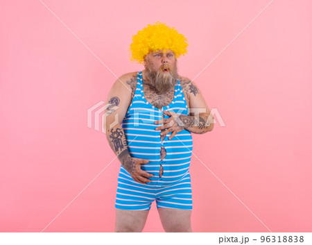 Happy man with yellow wig and swimsuit has stomachache 96318838