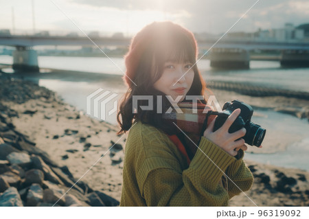 河川敷でカメラで写真を撮る若い女性の写真 96319092