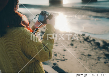 河川敷でカメラで写真を撮る若い女性の写真 96319442