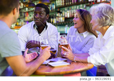 Happy diverse people drinking beer and eating tapas while spending time together in a bar 96319691