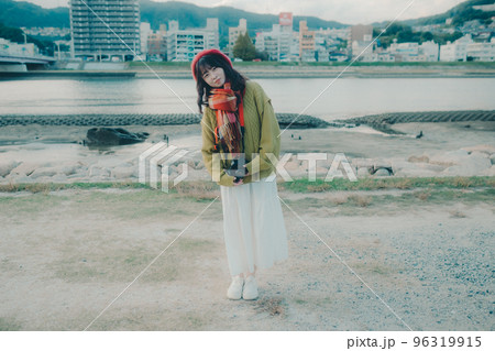 河川敷で一眼レフを使って写真を撮る若い女性の写真 96319915