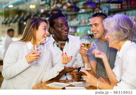 Cheerful international friends different ages enjoying pinchos and beer in the evening pub 96319932