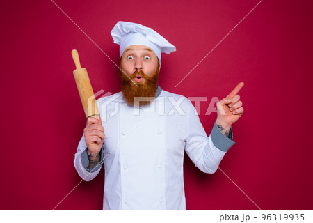 amazed chef with beard and red apron chef holds wooden rolling pin amazed chef with beard and red apron chef holds wooden rolling pin 96319935