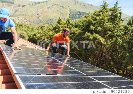 Workers assemble energy system with solar panel for electricity and hot water Workers assemble energy system with solar panel for electricity and hot water 96321289