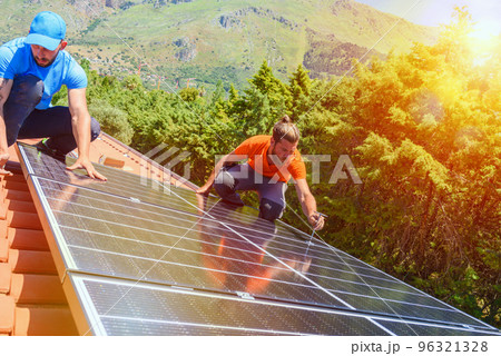 Workers assemble energy system with solar panel for electricity and hot water 96321328