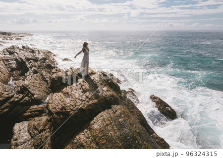 Romantic Bride, Brunette Girl in White Wedding Dress on Cliff Against Sea Background 96324315