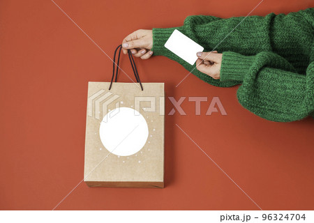 Xmas shopping concept. Woman's hands holding a gift bag and a credit card on a red background, Xmas shopping concept. Woman's hands holding a gift bag and a credit card on a red background, 96324704