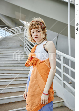 Young woman with curly hair looking at camera in urban city setting 96325824