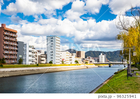 西蟹屋町と的場町に架かる大正橋下流域の猿猴川両岸を展望しています。遠方の橋の左はマツダスタジアムです 西蟹屋町と的場町に架かる大正橋下流域の猿猴川両岸を展望しています。遠方の橋の左はマツダスタジアムです 96325941