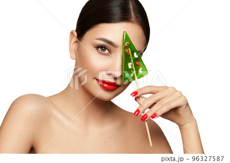 Beauty model girl eating Christmas tree shape lollipop 96327587