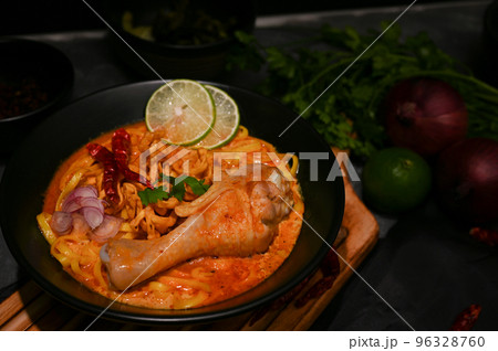 Creamy and slightly spicy yellow curry with chicken drumstick and vegetables. Khao Soi Kai. 96328760