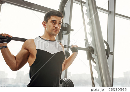 sport, bodybuilding, lifestyle and people concept - young man with barbell flexing muscles and making shoulder press lunge in gym sport, bodybuilding, lifestyle and people concept - young man with barbell flexing muscles and making shoulder press lunge in gym 96330546