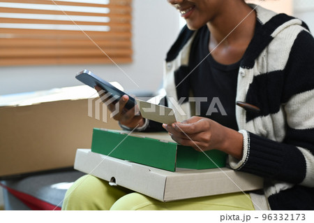 Cropped shot of young woman paying for online order with credit card on her smart phone. Digital lifestyle living concept 96332173