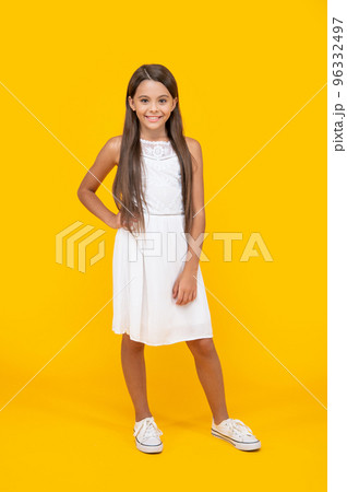 happy teen child in white dress standing on yellow background 96332497
