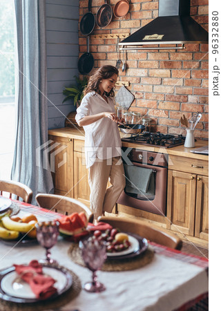 Woman in the kitchen cooking food in a frying pan. Woman in the kitchen cooking food in a frying pan. 96332880